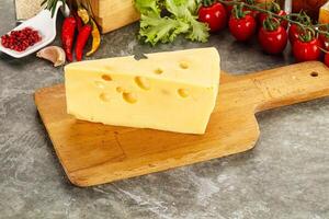 Swiss Maasdam cheese triangle over board photo