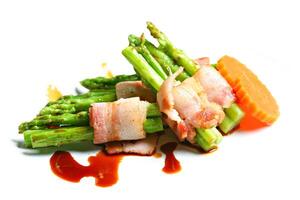 Grilled green asparagus wrapped with bacon in white background photo