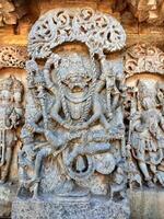 Stunning bas-relief of Ugra Narasimha, an avatar of Vishnu, adorns the Hoysaleswara Temple in Halebidu, India. The carving shows the fierce deity subduing demon king Hiranyakashipu with multiple arms. photo
