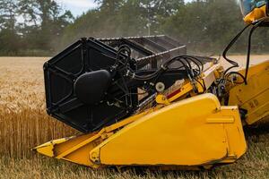 Process of gathering a ripe crop from the fields. Combine harvester in action on wheat field during the summer. Closeup photo