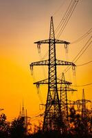 Aerial view drone shot. High voltage metal post. High-voltage towers in the forest with sunset and twilight sky with clouds background photo