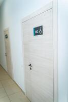 Perspective of a long corridor in office building. Doors of washrooms in hallway. Doors in office with wc signs. Entrance to restrooms in a factory photo
