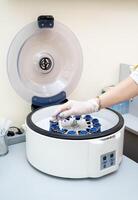 Getting ready. Close up of human hands putting the test tubes to centrifuge. Laboratory concept photo