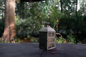 A beautiful decoration in the form of a large lantern and candlestick stands on a table illuminated photo