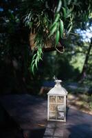 A beautiful decoration in the form of a large lantern and candlestick stands on a table illuminated photo