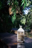 A beautiful decoration in the form of a large lantern and candlestick stands on a table illuminated photo