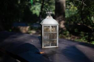A beautiful decoration in the form of a large lantern and candlestick stands on a table illuminated photo