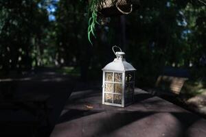 A beautiful decoration in the form of a large lantern and candlestick stands on a table illuminated photo