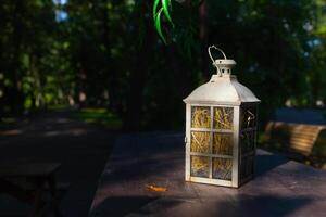 A beautiful decoration in the form of a large lantern and candlestick stands on a table illuminated photo