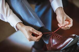 Handsome men tying their stylish shoe laces. The appearance of a business man. Details of the suit and the overall look. photo