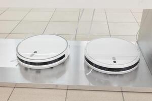Robotic vacuum cleaner working on carpet top view concept. Front Side View Modern Autonomous Smart Robotic Vacuum Cleaner Roomba. Self-Drive Cleaning Robot. Floor Cleaning System. Small Household photo
