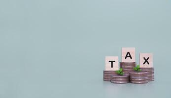 Wooden blocks with the word TAX on stack of coins. The concept of saving money for payment tax in future photo