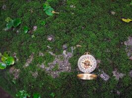 Compass on the rock with green moss background. The concept of world tourism day, Searching the right directions and Travel photo