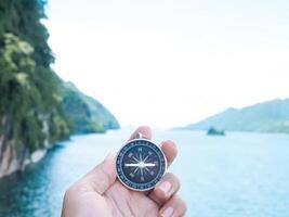 Close up of compass in woman hand with nature as background. The concept of world tourism day, Searching the right directions and Travel photo