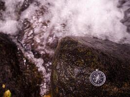 Compass on the rock with waterfall as background. The concept of world tourism day, Searching the right directions and Travel photo