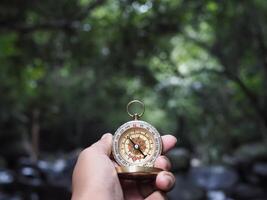 Hand holding compass with nature background. The concept of world tourism day, Searching the right directions and Travel photo