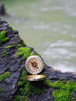 Compass on the rock with waterfall as background. The concept of world tourism day, Searching the right directions and Travel photo