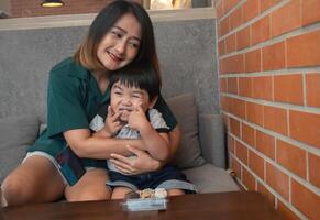 Mother and child sitting on the sofa, mother hugs her child and jokes with each other the child makes funny faces relaxing on holiday and happiness photo