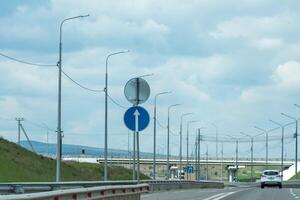 A road with a blue sign pointing to the right. The sky is cloudy and the road is empty. photo