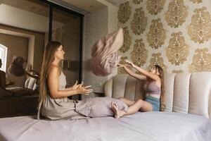 mom and daughter playing with pillows on a bed photo