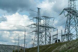 High voltage towers with sky background. Power line support with wires for electricity transmission. High voltage grid tower with wire cable at distribution station. Energy industry, energy saving photo