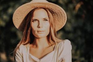 Woman with straw hat stands in front of vineyard. She is wearing a light dress and posing for a photo. Travel concept to different countries photo