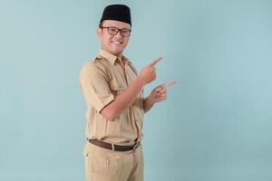 Happy Indonesian government worker man wearing khaki uniform pointing to the copy space beside him. photo