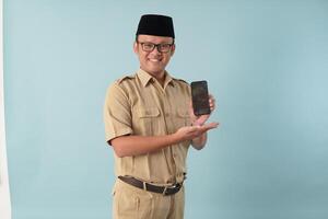 Smiling government worker man wearing khaki uniform presenting copy space on smartphone. photo