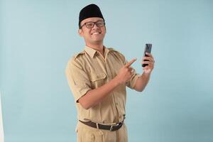 Happy government worker man wearing khaki uniform doing call while pointing to smartphone. photo
