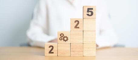 2025 year block with gear icon. Business Process, Team, teamwork, Goal, Target, Resolution, strategy, plan, Action, motivation, change, brainstorm and New Year start concepts photo