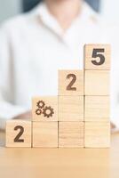 2025 year block with gear icon. Business Process, Team, teamwork, Goal, Target, Resolution, strategy, plan, Action, motivation, change, brainstorm and New Year start concepts photo