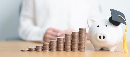 Money saving for Education, Scholarship, Student loan and debt and study future plan concept. Coins stack growing up with piggy and graduation hat on table photo