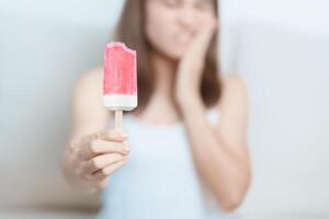 Teeth Sensitive to Cold concept. woman hold Ice cream and having toothache and pain after eat. Tooth Decay or Gum Disease, Grinding Teeth and Stress, Exposed Nerve Roots, Crack and Receding Gums photo