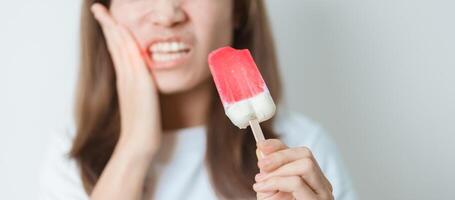 Teeth Sensitive to Cold concept. woman hold Ice cream and having toothache and pain after eat. Tooth Decay or Gum Disease, Grinding Teeth and Stress, Exposed Nerve Roots, Crack and Receding Gums photo