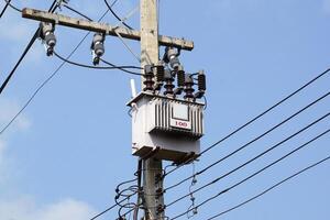 Power transformer installed on electric pole on daytime sky background. Soft and selective focus. photo