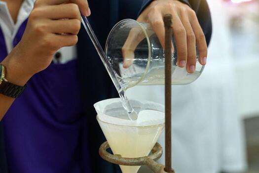 Experiment to separate mixed substances by pouring substances into a separator funnel through filter paper. Solid particles are placed on the filter paper. The liquid will flow into the beaker below. photo
