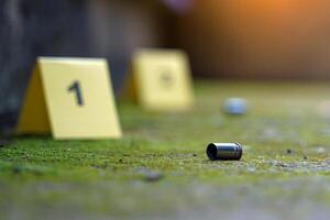 Bullet casings fell on the moss growing on the cement floor and blurry background of the evidence number plate at the scene. Concept of investigation, forensic science. photo
