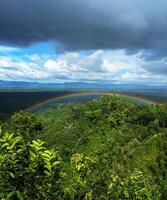 Rainbow bridge over mountains in cloudy sky photo