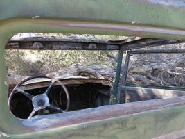 Looking Inside at the Steering Wheel in an Abandoned Old Car in the Desert photo