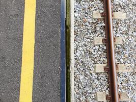 half asphalt and half railroad tracks. top view of indonesian railway station platform photo