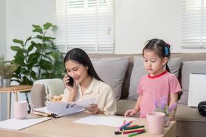Focused Mother Balancing Professional Tasks While Daughter Observes photo