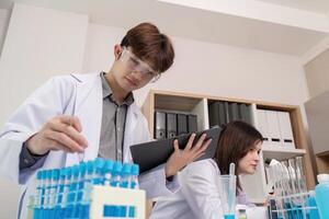 Young Scientist Managing Laboratory Analysis with Test Tubes and Digital Tools photo