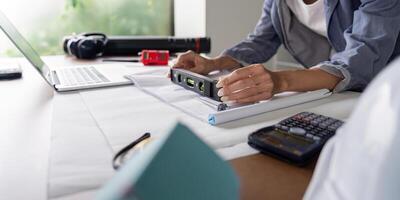 Woman Engineer Ensuring Precision on Blueprint Layouts with Level Tool and Calculator photo