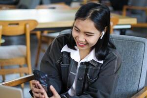 excited asian woman working with laptop from cafe using smartphone to browsing internet and reading news photo