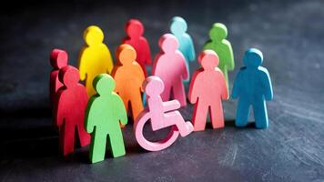 diversity and inclusion concept with wooden people figures of different color including wheelchair user photo