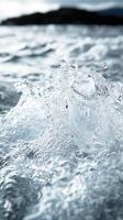 Crystal clear water splashing on ocean surface with mountain shore in the background photo