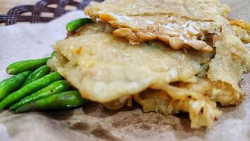 a fried fish and green beans on a paper plate photo