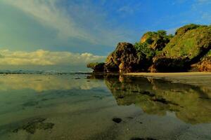 a beach with rocks and water reflecting in the sand photo