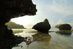 a rock formation on the beach with water and rocks photo