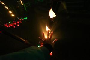 a person holding a lit candle in the dark photo
